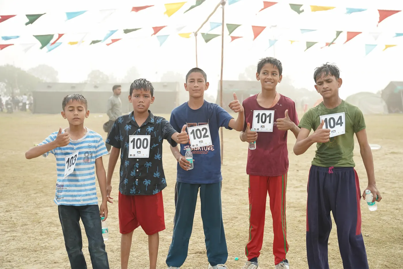Young runners with their bibs giving thumbs up.