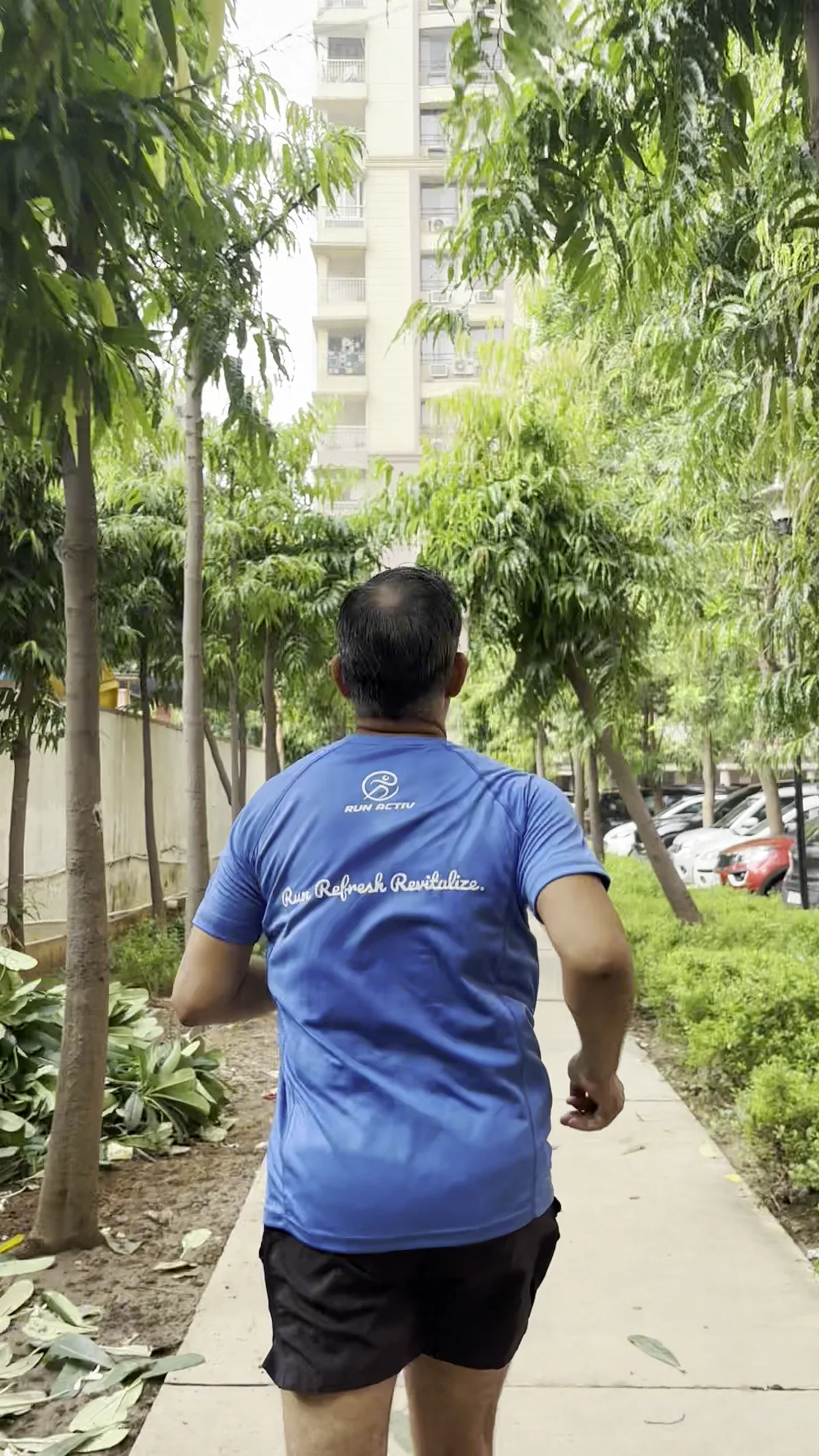 A RunActiv runner in the club shirt on a tree-lined path.